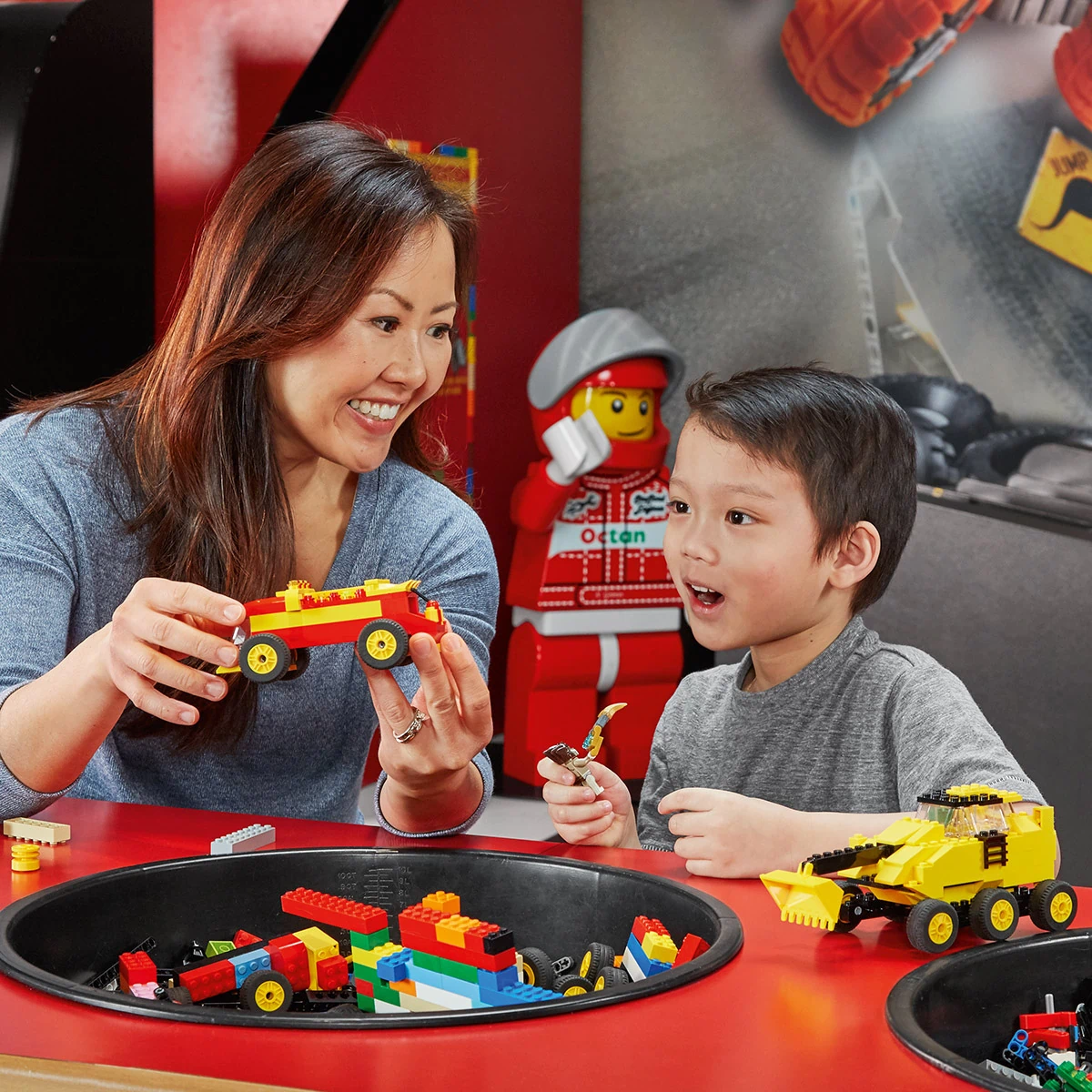 LEGOLAND® Discovery Centre Berlin, eine Mutter spielt mit ihrem Sohn mit Legosteinen, sie hält ein rotes Auto in den Händen.