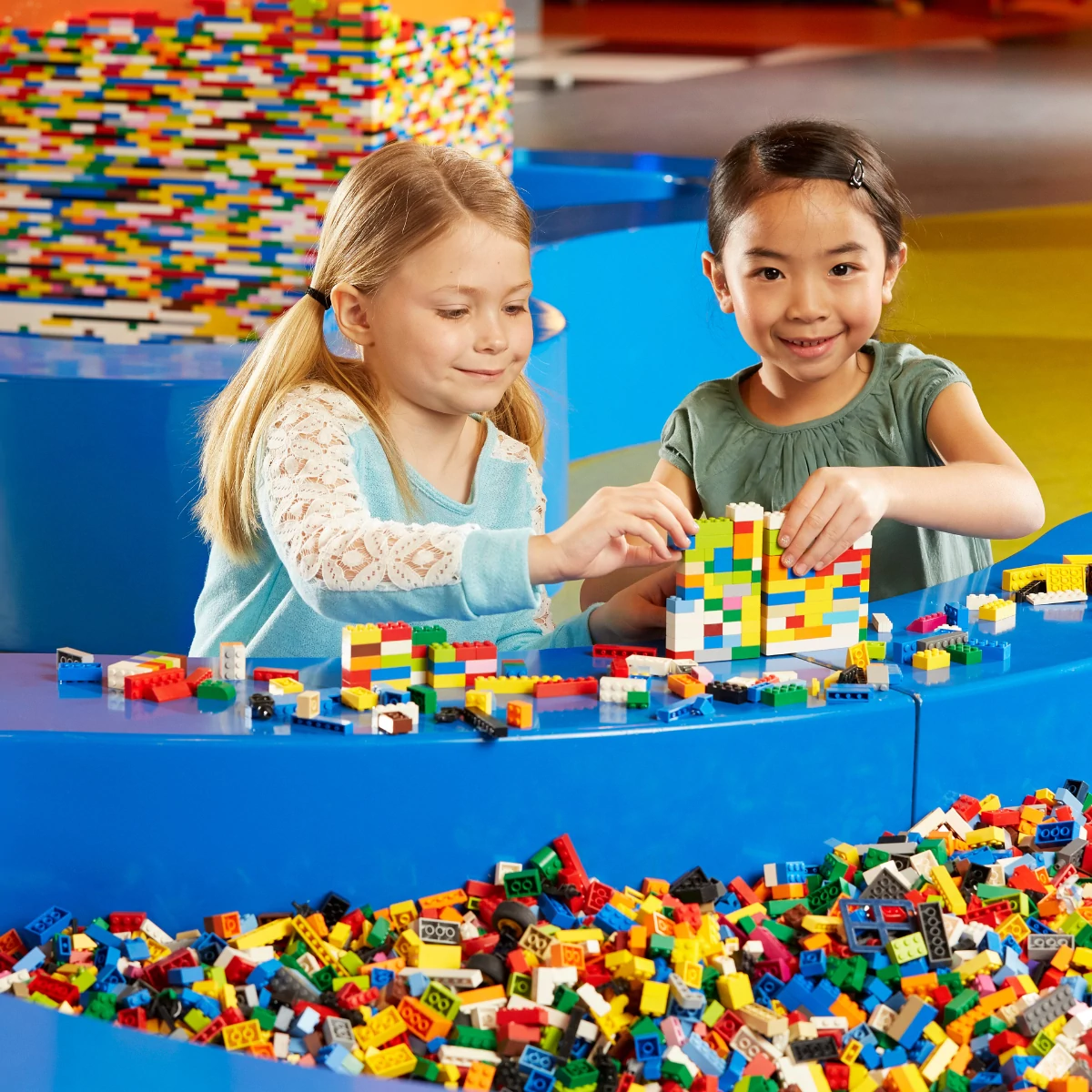 LEGOLAND® Discovery Centre Berlin, zwei Kinder spielen mit bunten Legosteinen und lächeln