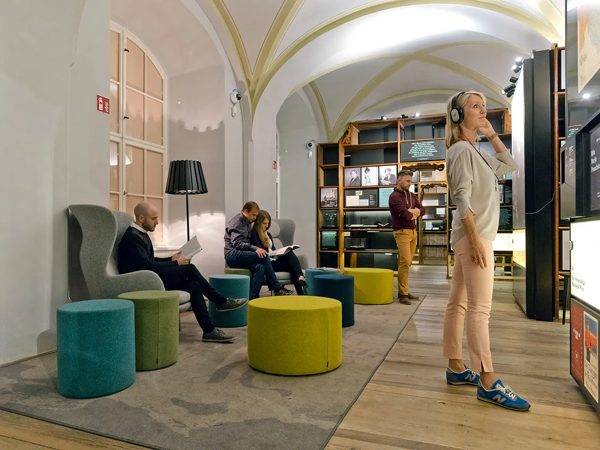 Literaturmuseum der Österreichischen Nationalbibliothek, Wien, Ausstellung, Frau steht mit Kopfhörern vor einem Ausstellungsstück, grüne Sitzgruppe auf der Besucher sitzen