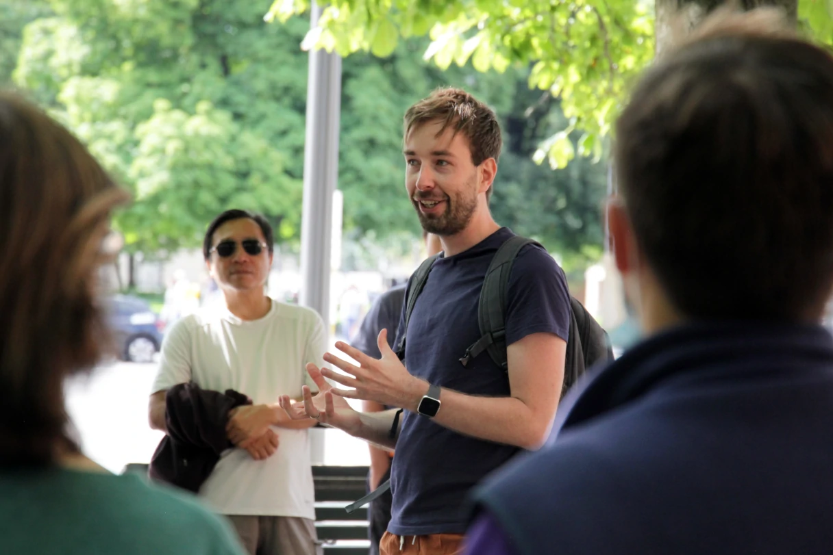 Matti erklärt seiner Gruppe während der Stadtführung etwas, Mann in dunkelblauem T-Shirt spricht zu einer Gruppe
