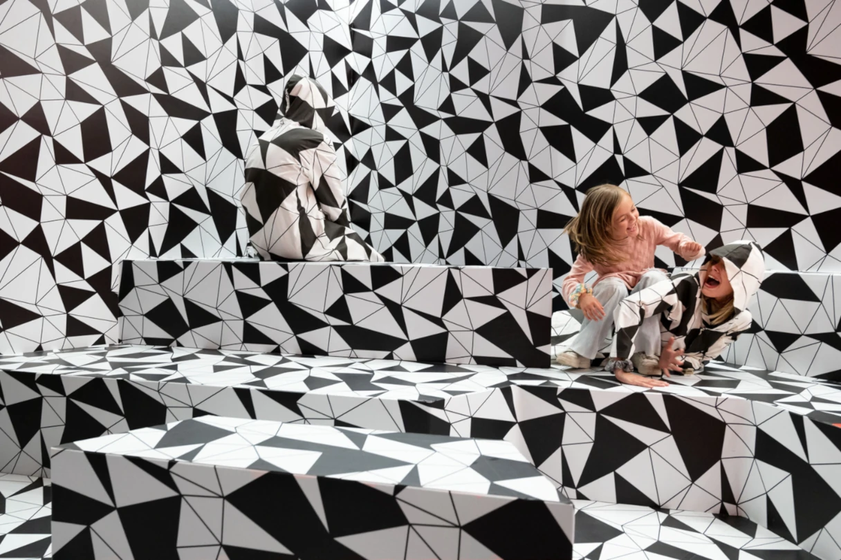 Paradox Museum Berlin, Frau sitzt in einem schwarz weißen Raum und verschwindet fast