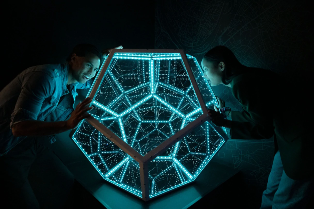 Paradox Museum Berlin, zwei Besucher stehen an einem beleuchteten Tetraeder