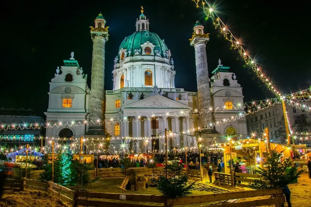 St. Charles's Church in Vienna and the Christmas market around it. Colorful lights, Christmas trees, and animal enclosures.