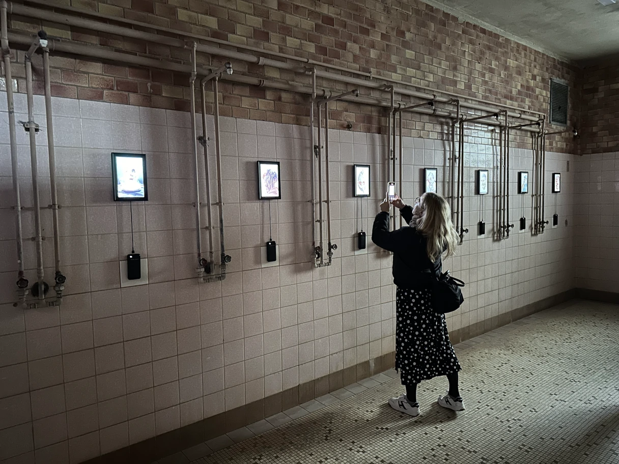 Stadtbad RELOADED: AMBILIGHT, woman standing in the former shower rooms where digital artworks now hang