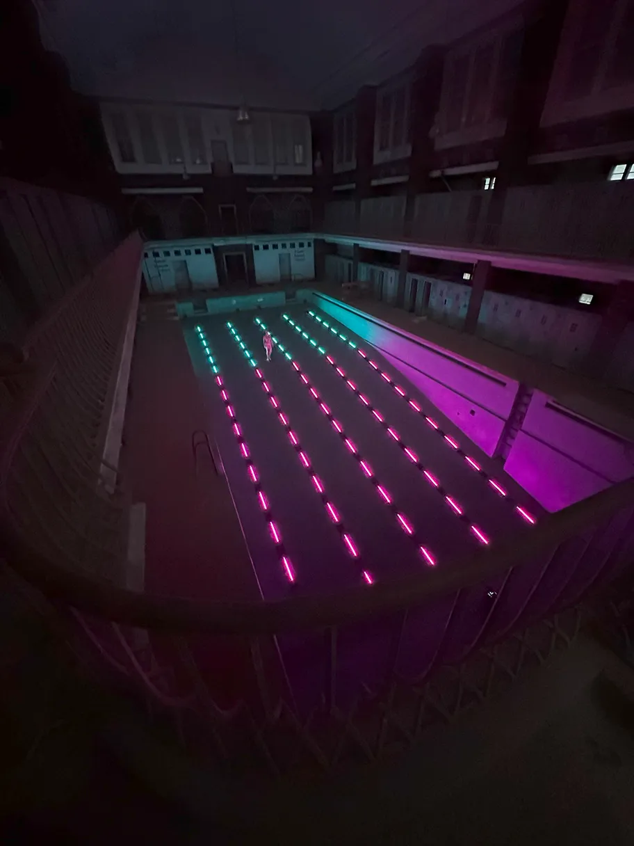 Stadtbad RELOADED: AMBILIGHT, angeleutetes leeres Schwimmbad in pink und türkis