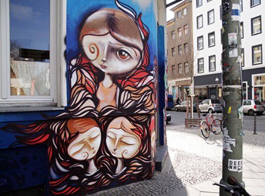 Street art, house corner is painted with three women heads