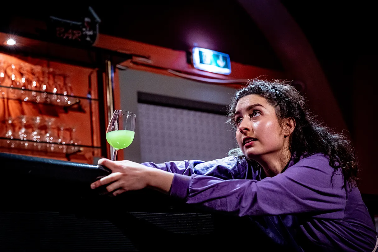 Titanic oder wie tief kann man sinken, play, Theater Drachengasse, Woman in purple blouse sits at the bar with a cocktail