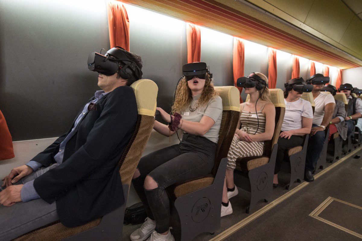 TimeRide, virtual reality tour in 80s bus, visitors sitting on seats, have virtual reality goggles on
