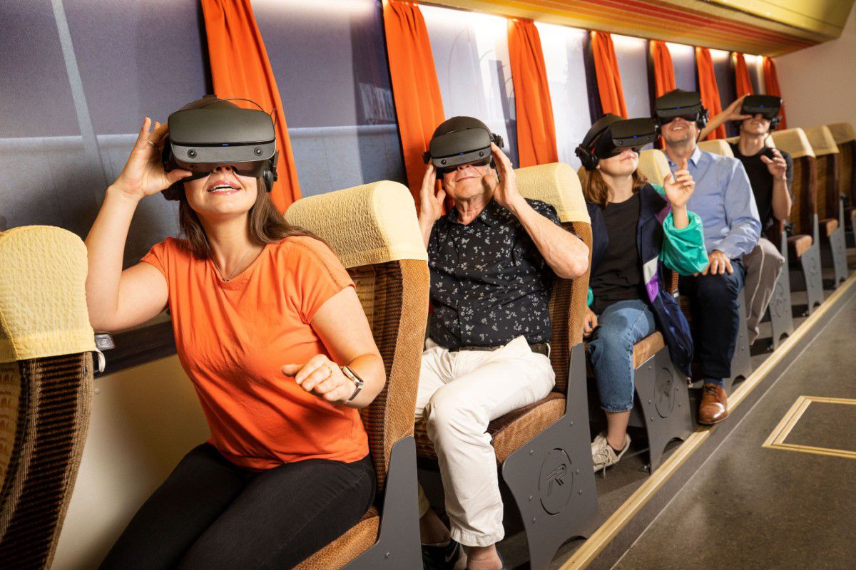 TimeRide, virtual reality tour in 80s bus, visitors sitting on seats, have virtual reality goggles on