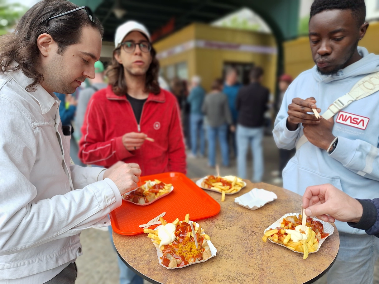 3 people eat currywurst and chips on their culinary bike tour