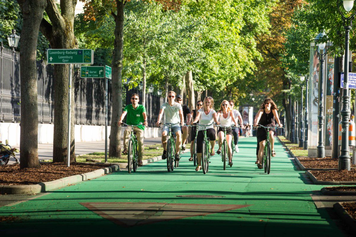 Vienna Explorer Tours & Day Trips, Gruppe Touristen fährt mit grünen Fahrrädern auf einem grünen Radweg
