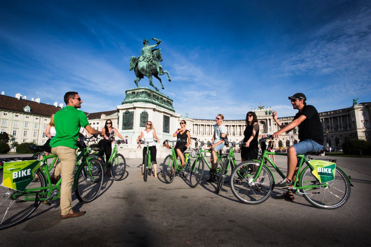 Vienna Explorer Tours & Day Trips, Wien Fahrradtour, Gruppe steht mit grünen Fahrrädern vor einem Reiterdenkmal auf dem Heldenplatz