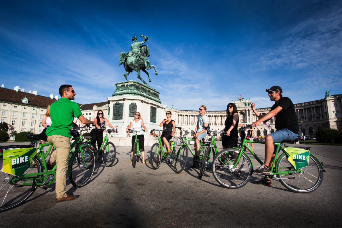 Vienna Explorer Tours & Day Trips, Vienna bike tour, group stands with green bikes in front of an equestrian monument on Heldenplatz