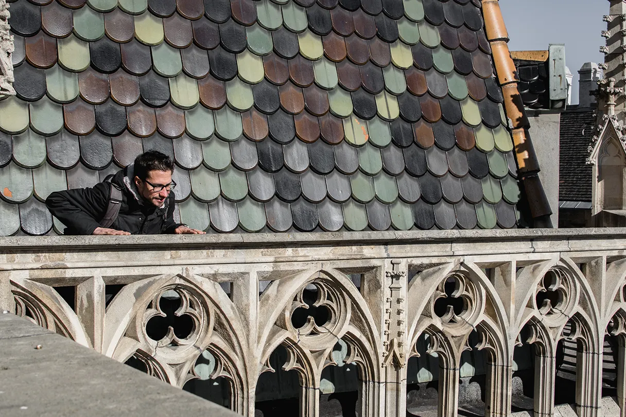 Tour auf den Stephansdom mit Wien mal anders. Ein Mann steht auf dem Dach und schaut nach unten. Im Hintergrund sind die bunten Dachschindeln zu erkennen.