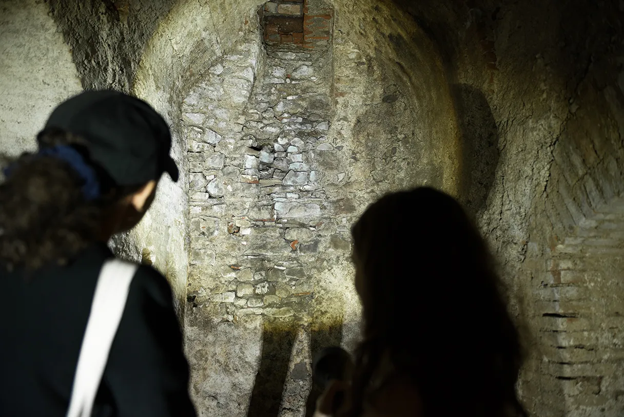 Vienna with a difference, tour into the Viennese underworld, two participants stand in the dark cellar with flashlights and shine on the masonry