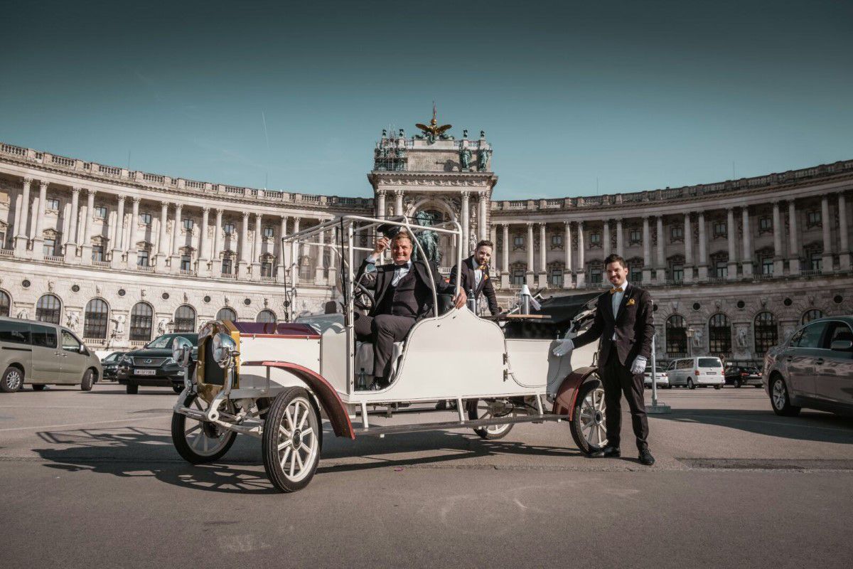 Vienna with a difference, tour with the City Oldtimer, Heldenburg, parking lot, sunny day, chauffeur and owner looking into the camera