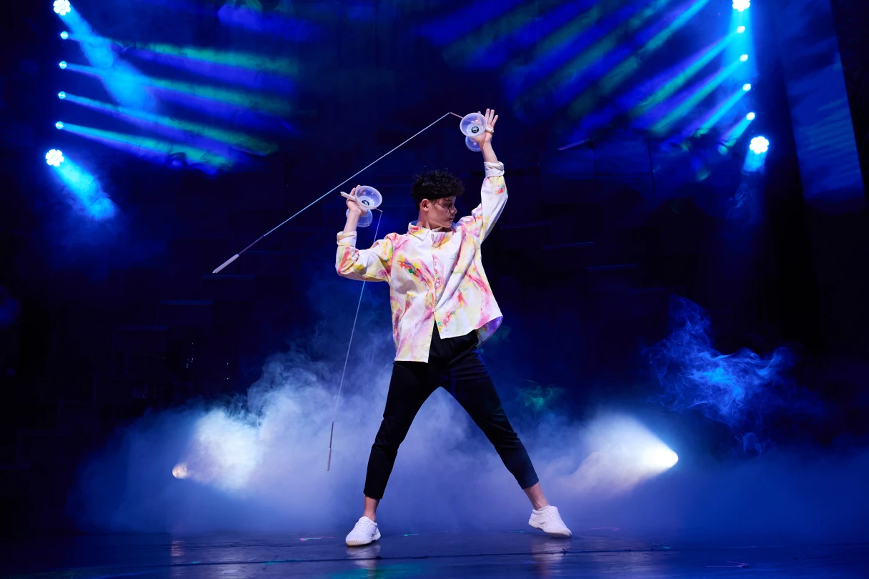 Wintergarten Berlin Varieté, Tim Leong, juggles with a diabolo and stands on the stage, which is illuminated blue and foggy