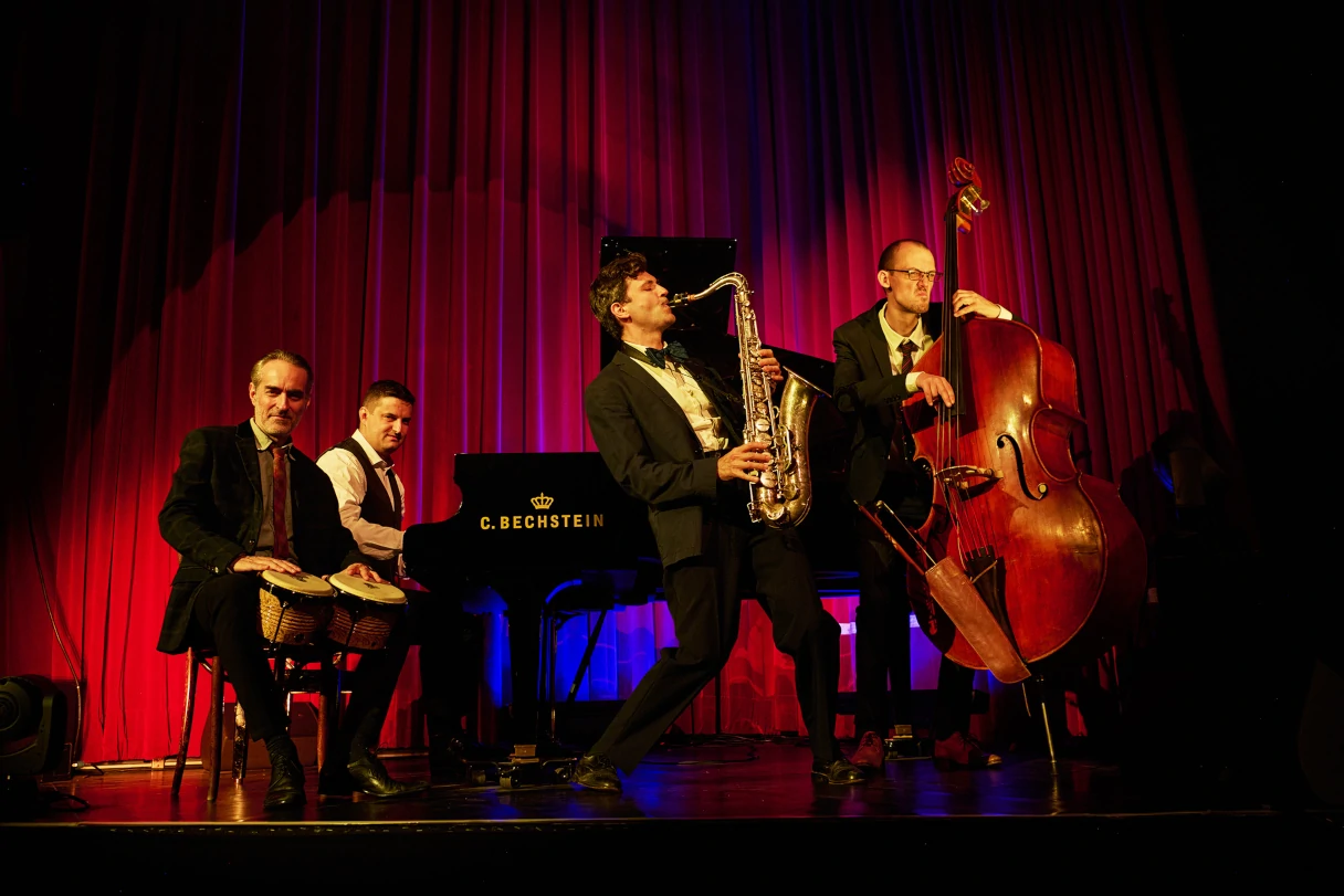 Wintergarten Berlin Varieté, band on stage with double bass, saxophone, piano and bongos, red curtain