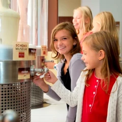 SchokoMuseum Vienna, children stand in front of various chocolate fountains and test the different types of chocolate