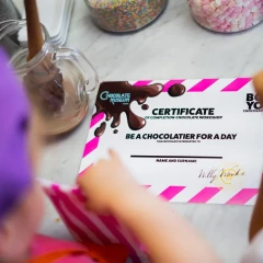 Chocolate Museum Vienna, child sitting at a table, bird's eye view, in front of him is an A4 piece of paper with “Certificate - Chocolatier for a day” written on it