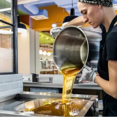 Zuckerlwerkstatt, woman has a large pot in her hand and pours the liquid yellow sugar mass onto the work surface to make Zuckerl