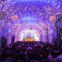 Schönbrunn Palace Concerts, Vienna, purple-lit Orangery, audience looking at the stage