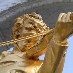 Close-up of the golden Johann Strauss statue. You can see Strauss with the violin in his hand.