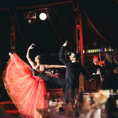 A dancer at the Strauss Dinner Show lifts her leg and swings her red dress into the air.